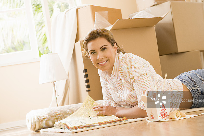 年轻女人躺在地板上吃中餐，微笑，肖像图片素材