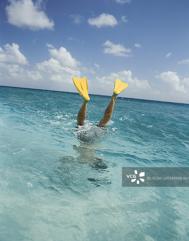 男人戴着脚蹼，在海里倒立，低角度拍摄图片素材