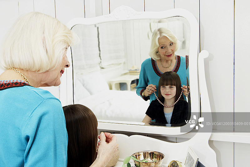 祖母在镜中给孙女试戴项链图片素材