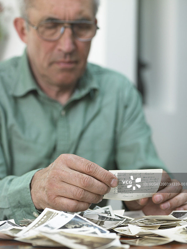 老年男人坐在桌旁看照片（聚焦手部）图片素材