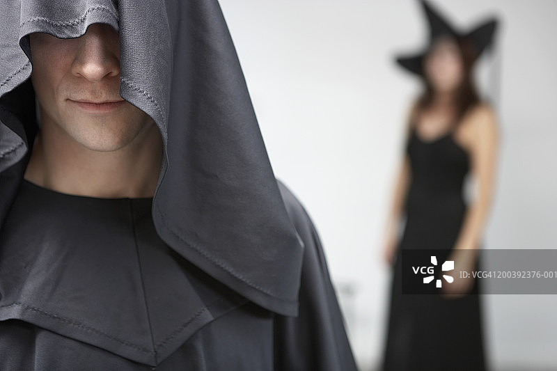 男人穿带帽服装，女人在背景中图片素材