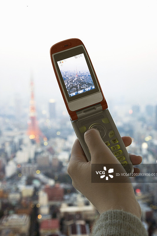 女人用手机拍摄东京天际线图片素材