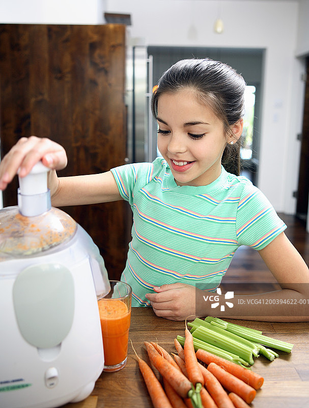 年轻女孩在厨房榨蔬菜汁图片素材