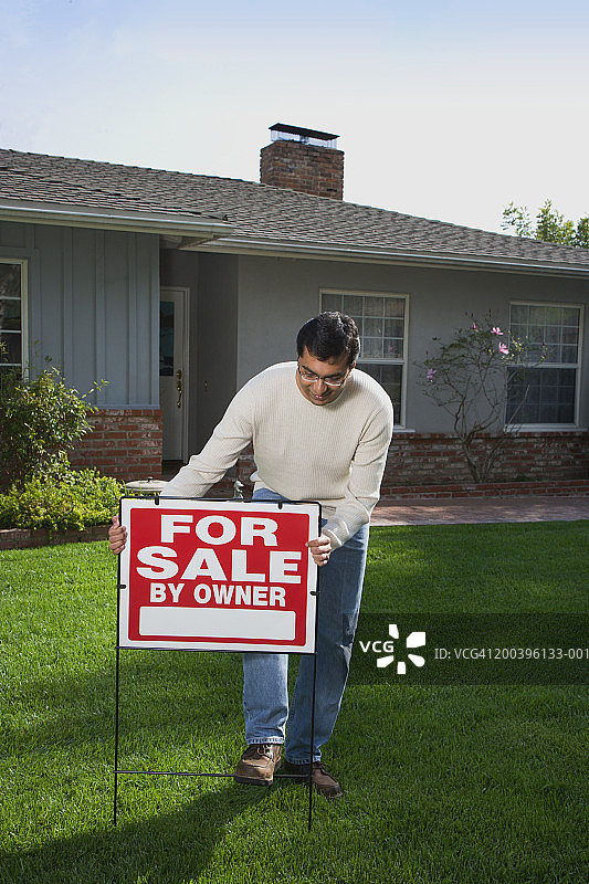 男子在房屋前院放置“出售”标志图片素材