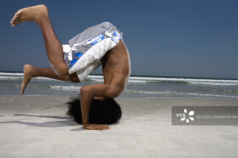 在海滩边做倒立的青少年男孩（13-15岁）侧视图图片素材