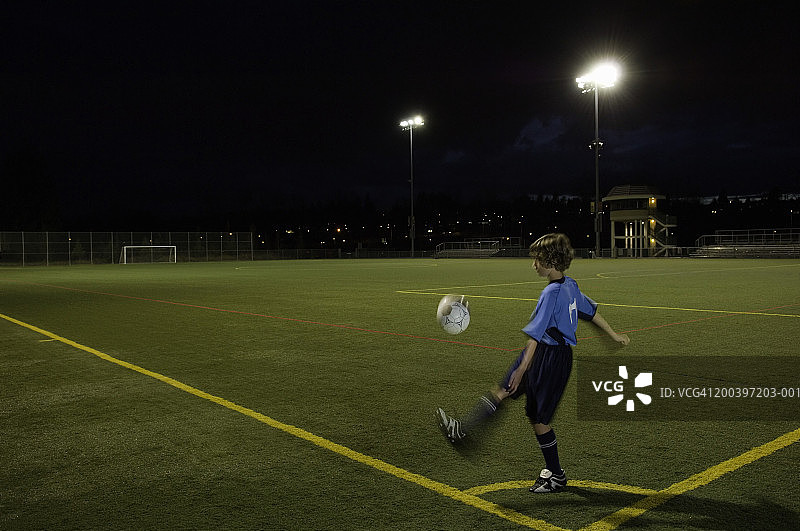 在球场上踢足球的男孩（10-12岁），夜晚（动态模糊）图片素材