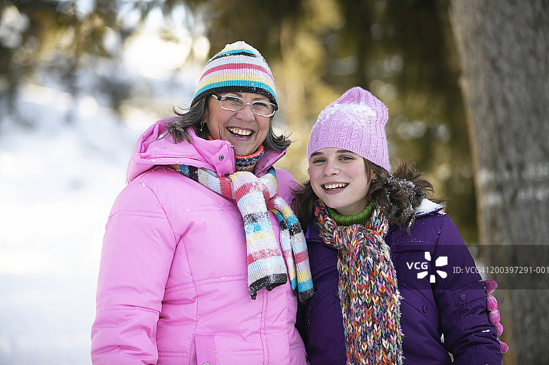 祖母和孙女(12-14岁)站在雪地里微笑图片素材