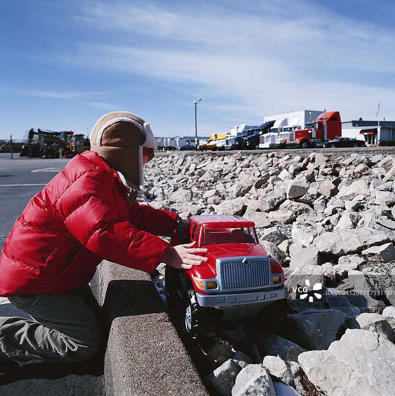在卡车停车场旁玩玩具卡车的男孩（4-6岁）图片素材