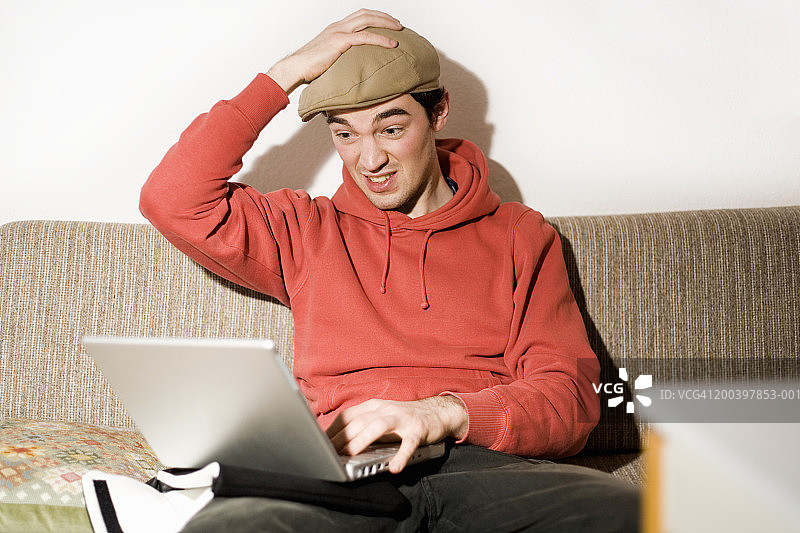 坐在沙发上使用笔记本电脑的年轻男人图片素材
