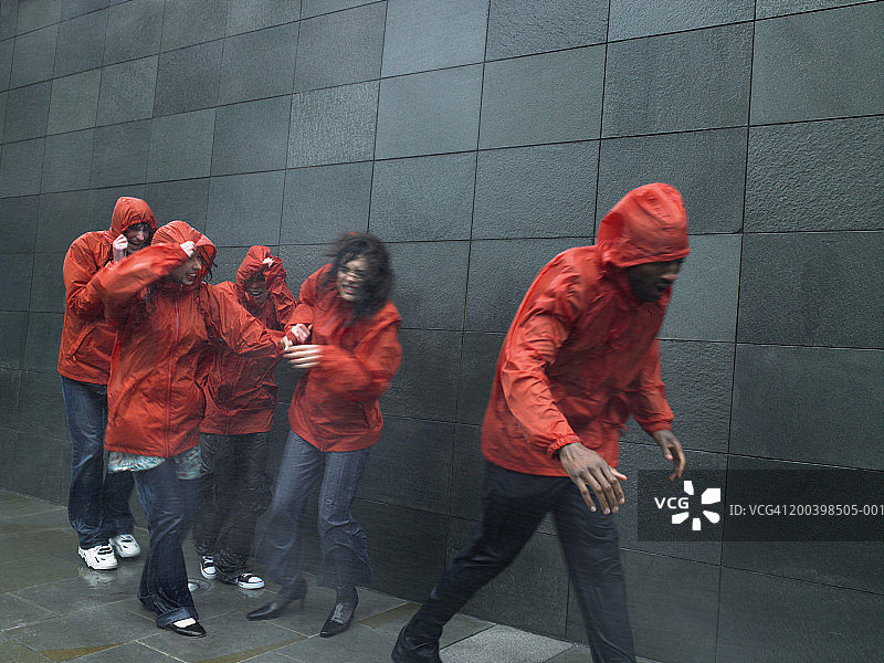 穿着防风外套逆风行走的人群图片素材