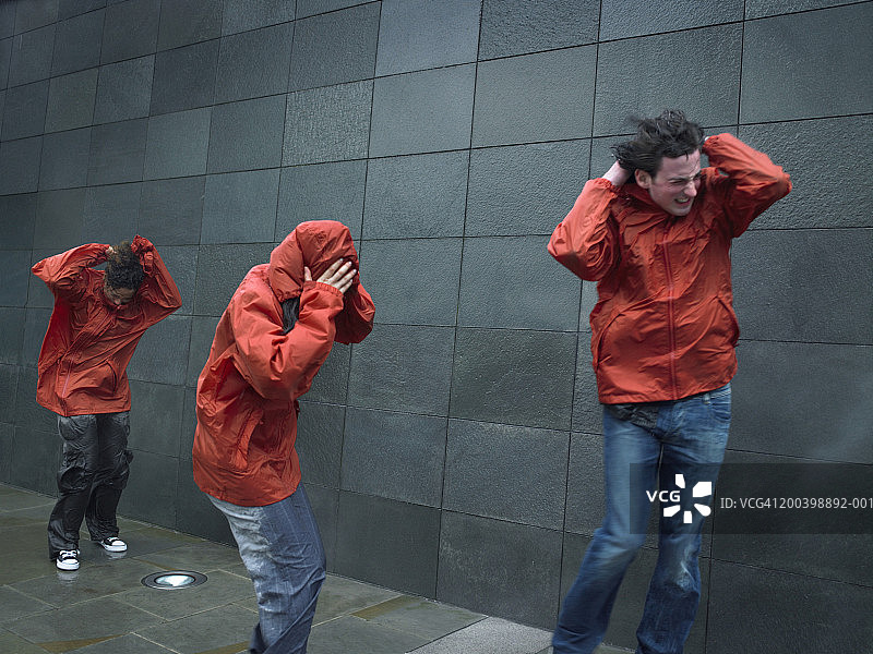 身穿防风夹克的年轻男女在风中艰难前行图片素材