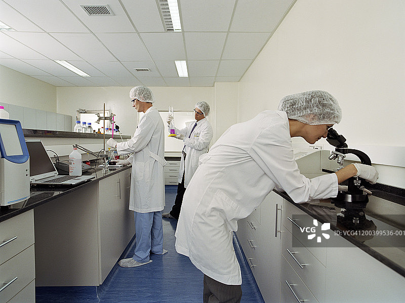 在科学实验室工作的女人和两个穿着实验服的男人图片素材