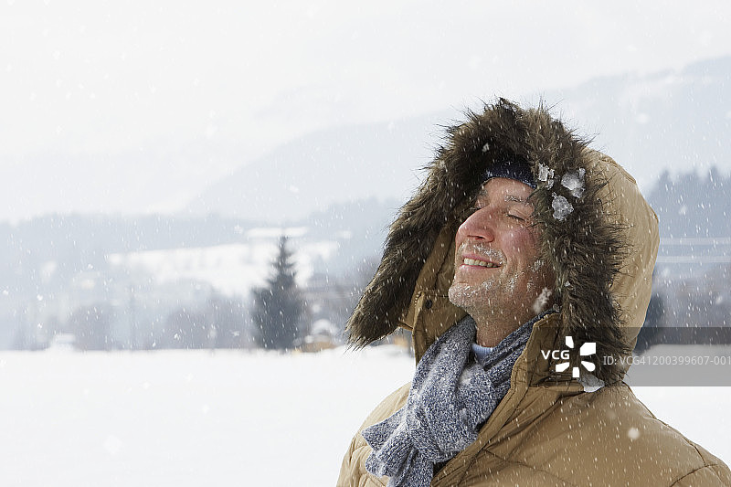 雪地风景中微笑的连帽夹克男人特写图片素材