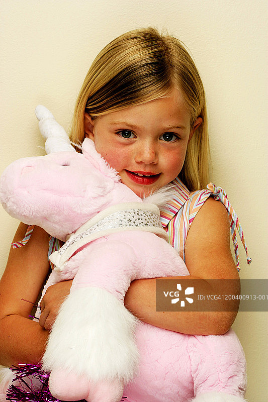 抱着玩具独角兽的女孩（3-5岁），肖像特写图片素材