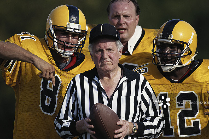 三名足球运动员与成熟裁判交谈并示意图片素材