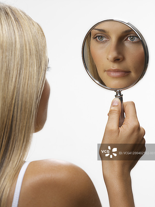 年轻女人照镜子（焦点在倒影上）图片素材
