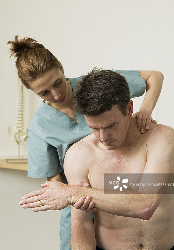 女按摩师正在调整成熟男性的背部图片素材
