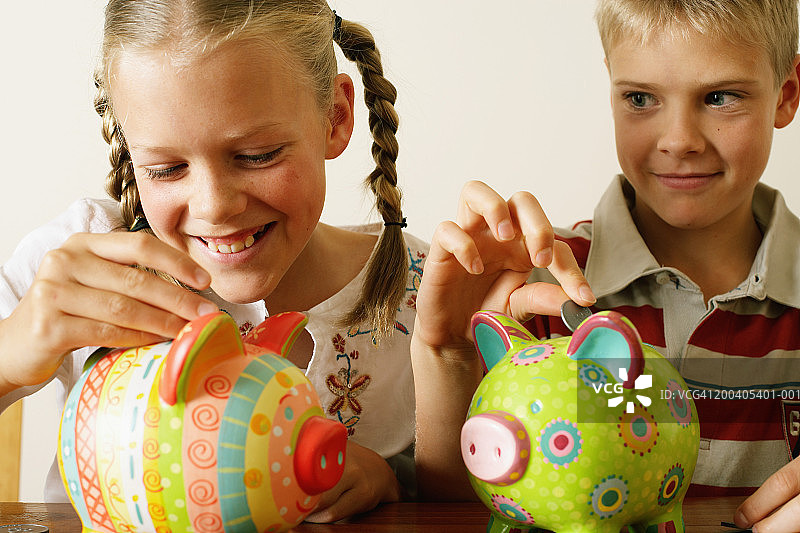 姐弟（10-12岁）往储蓄罐里投币图片素材