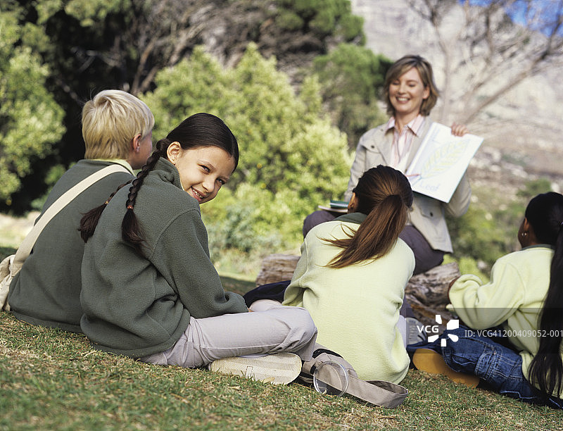 中年妇女和孩子们坐在草地上图片素材