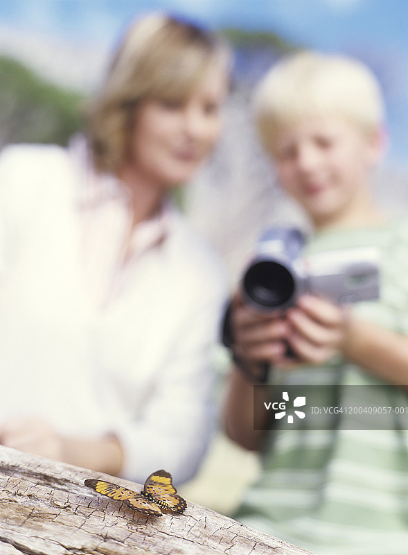 男孩（8-10岁）和母亲用摄像机拍摄蝴蝶图片素材
