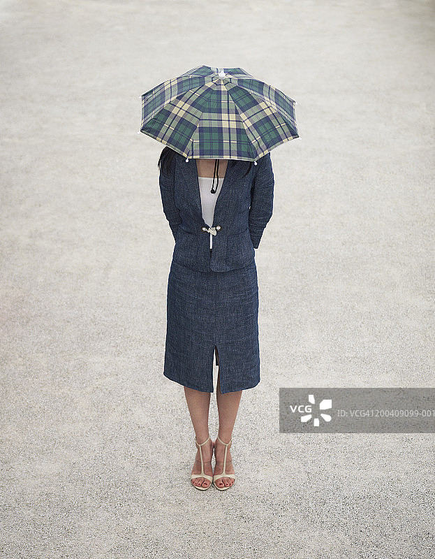 戴着雨伞帽，遮住脸的女人，高角度拍摄图片素材