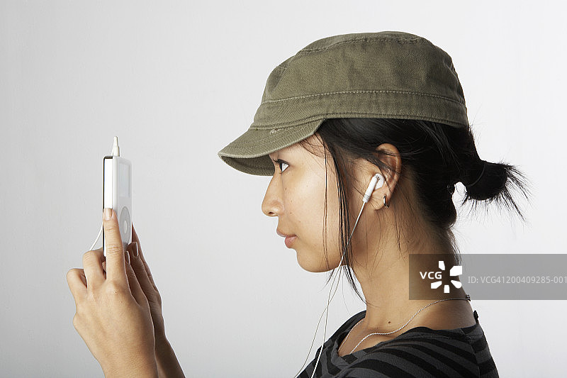 看着并听着音乐播放器的女人，侧视图图片素材