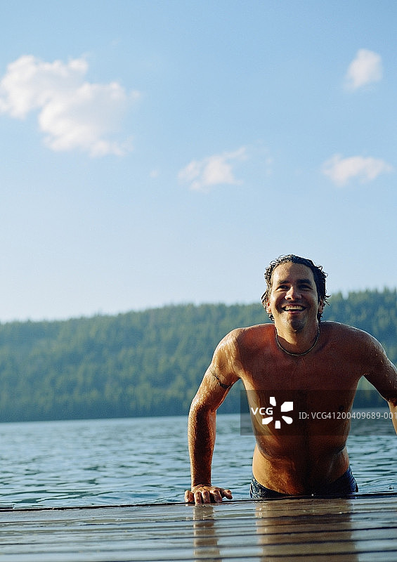 男人笑着从水中把自己拉到码头上图片素材