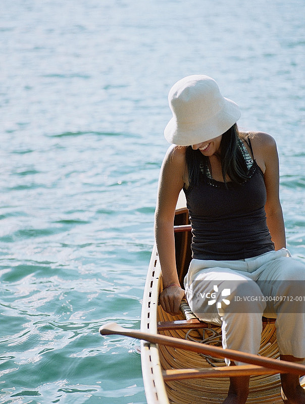 戴帽女子在湖上划独木舟微笑图片素材