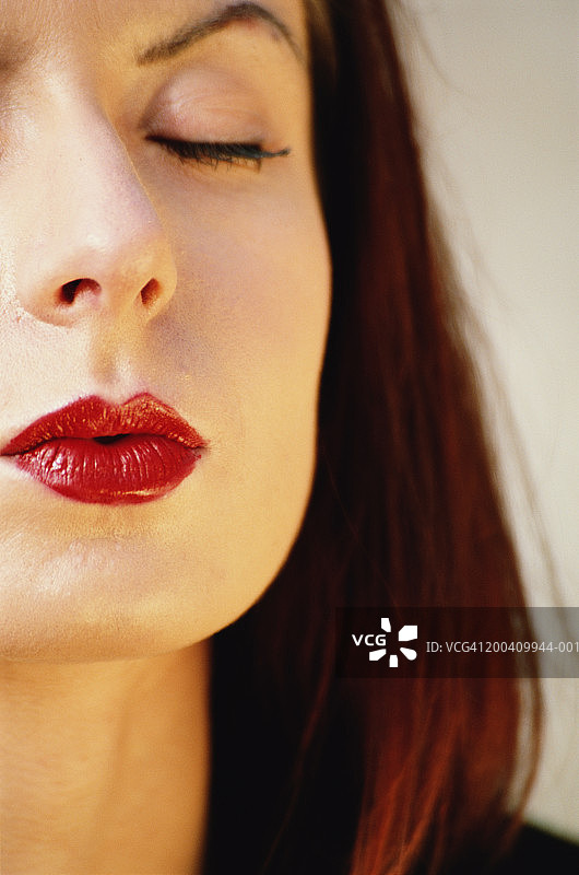 涂着红色口红，闭着眼睛的年轻女人特写图片素材