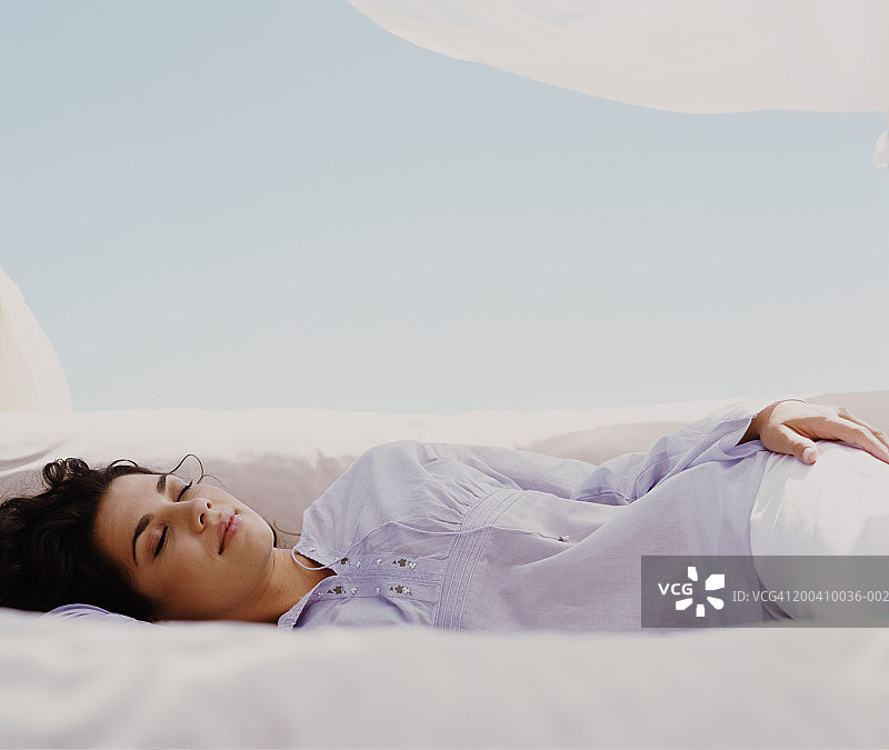 年轻女人侧卧闭眼，低角度拍摄图片素材