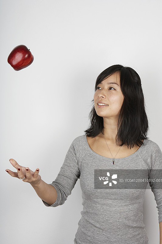 向上扔苹果并微笑的女人图片素材
