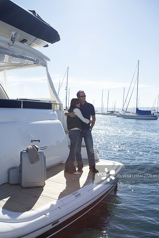 中年夫妇站在游艇上，彼此搂着图片素材