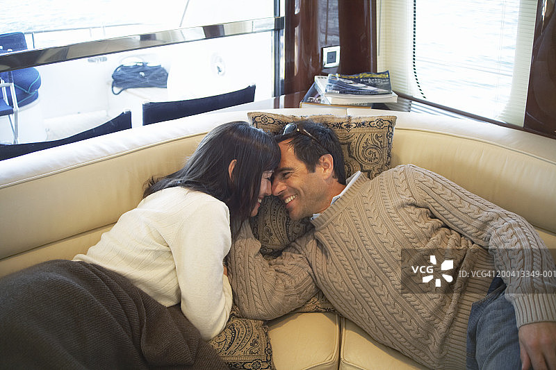 游艇座位上头靠着头微笑的一对情侣图片素材
