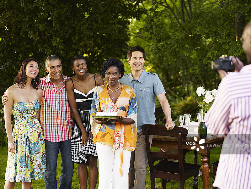 男人在户外桌旁拍摄一群拿着蛋糕的成年人图片素材