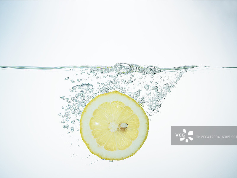 柠檬片落入水中特写镜头图片素材