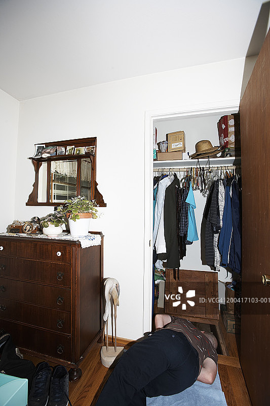 躺在地板上，看向壁橱爬行空间的年轻男人图片素材