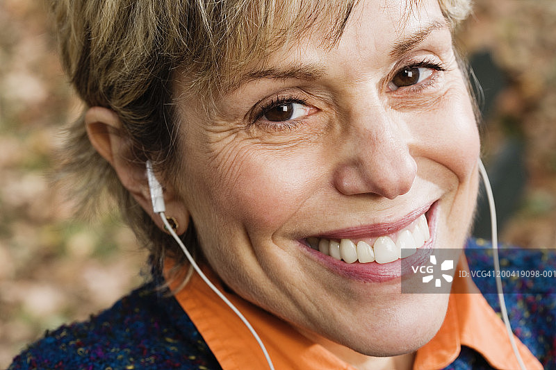 戴着耳机微笑的中年妇女肖像图片素材