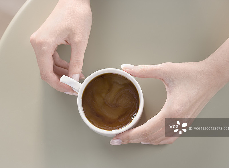 女人在桌子上拿着咖啡杯的特写俯视图图片素材