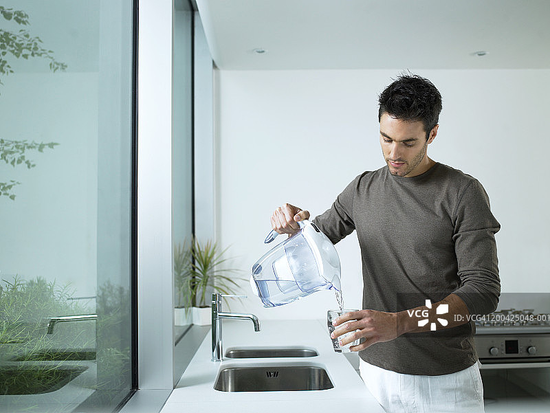 在厨房倒过滤水的男人图片素材