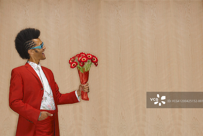 戴墨镜手捧非洲菊的男人图片素材