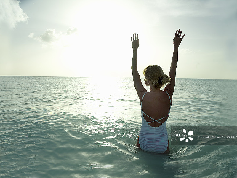 女人在海边抬起手臂（背影）图片素材