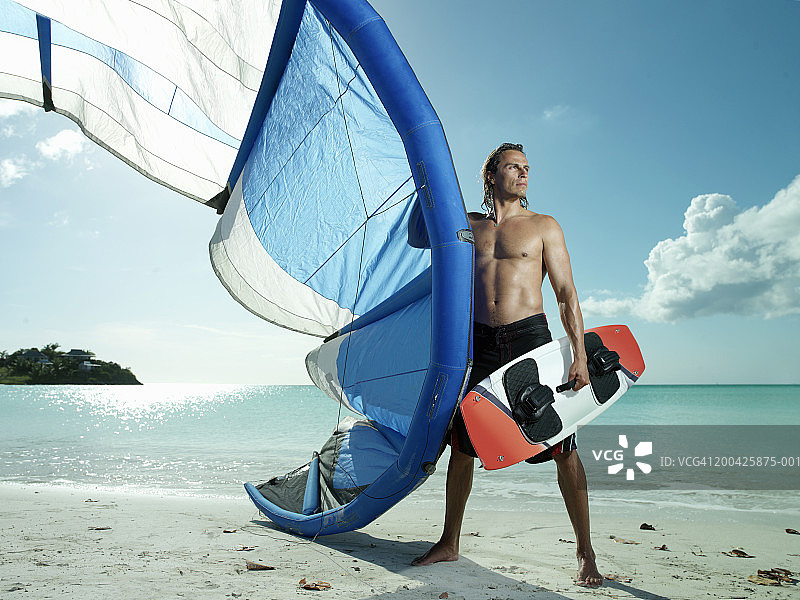 在海滩上带着风筝冲浪装备的男人图片素材