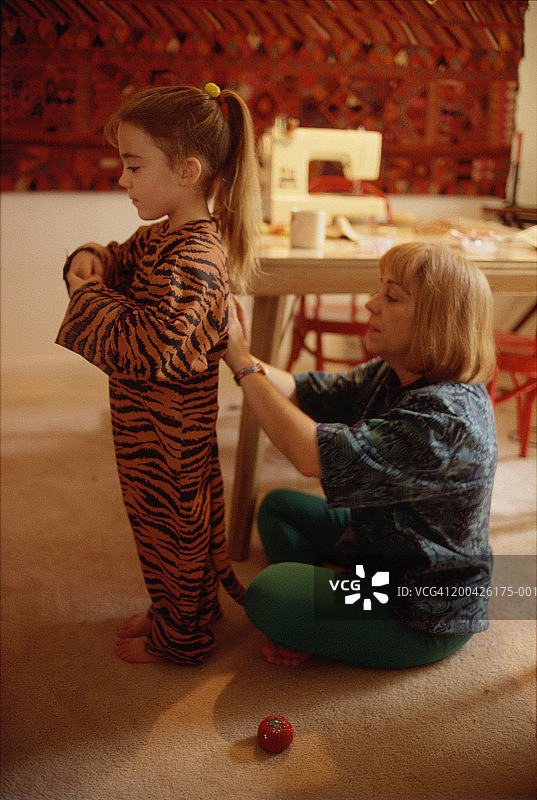 母亲给4-6岁的女儿试穿老虎服装（侧面）图片素材