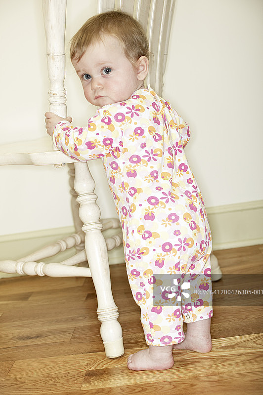 扶着椅子回头看的小女孩（12-15个月）图片素材
