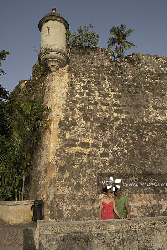 年长的男人和中年男人站在殖民时代堡垒的墙壁附近，地点：波多黎各圣胡安图片素材