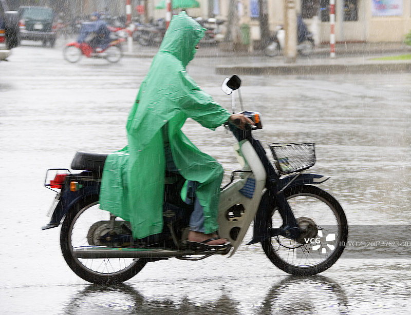 雨中骑摩托车的人（模糊运动），侧视图图片素材
