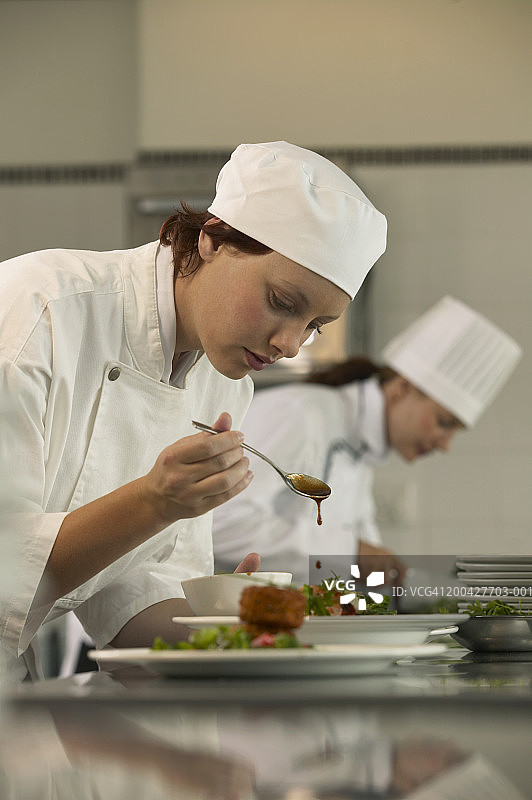 年轻女厨师在厨房准备食物（侧视图，特写）图片素材