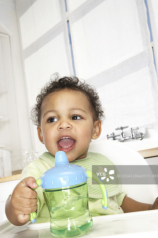 坐在高脚椅上拿着杯子的男婴（18-24个月），低角度视角图片素材