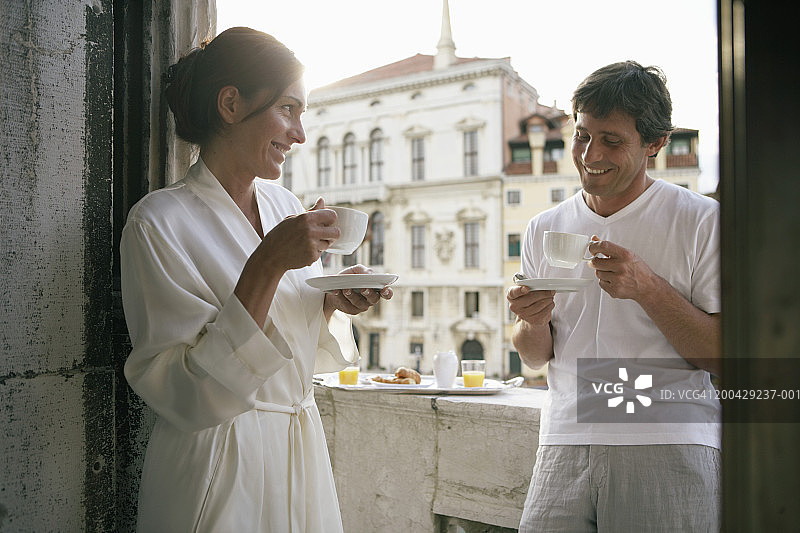 意大利威尼斯阳台上喝咖啡的微笑情侣图片素材