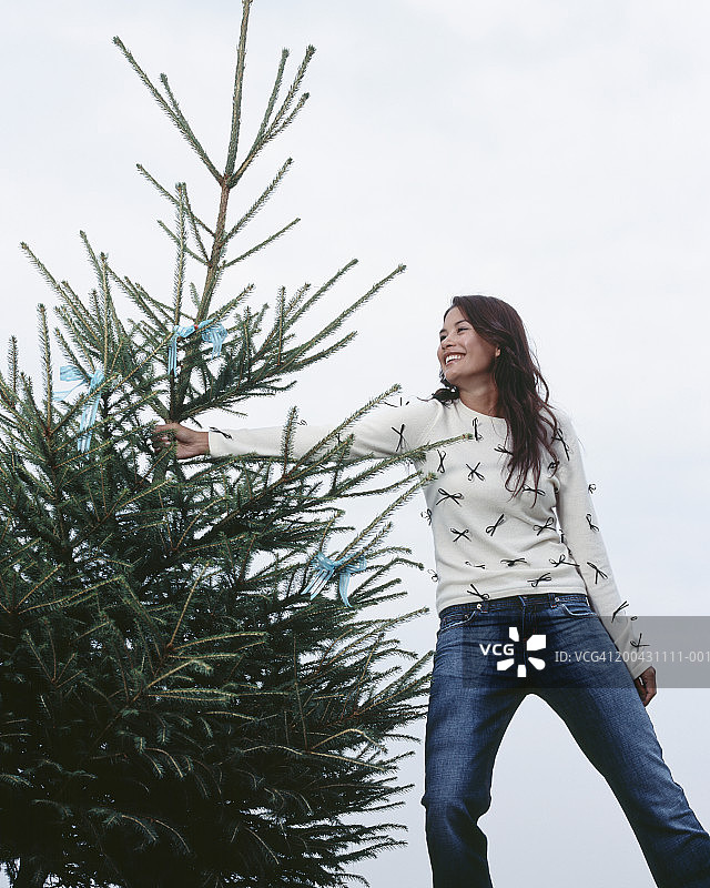 手捧圣诞树（松属植物），微笑的年轻女人图片素材